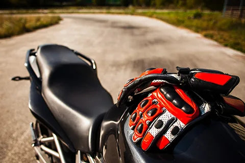 Best motorcycle gloves for riders, featuring red gloves on a black motorbike