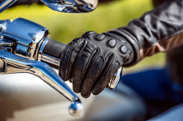 Close-up of a gloved hand on a motorcycle handlebar with a blurred background